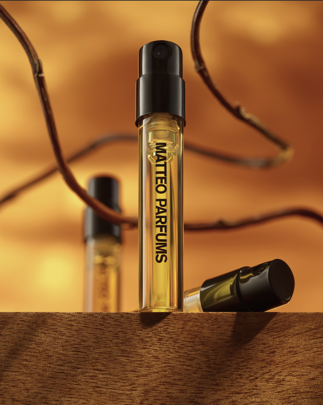 Three sample perfume sprayers by MATTEO PARFUMS on a wooden surface with a warm background