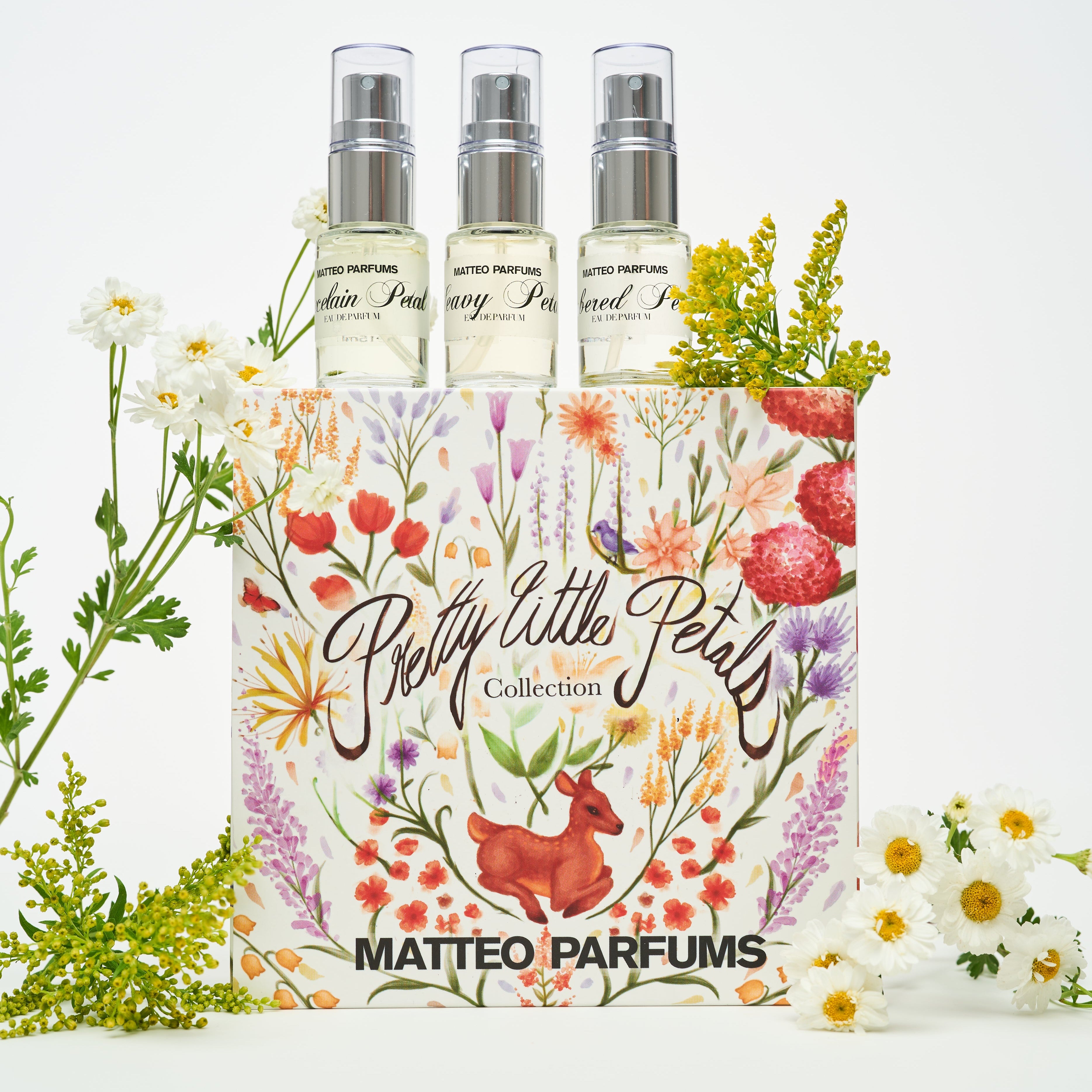 Three petite perfume bottles with a decorative box labeled 'Pretty Little Petals Collection' by MATTEO PARFUMS with white flowers on a white background.