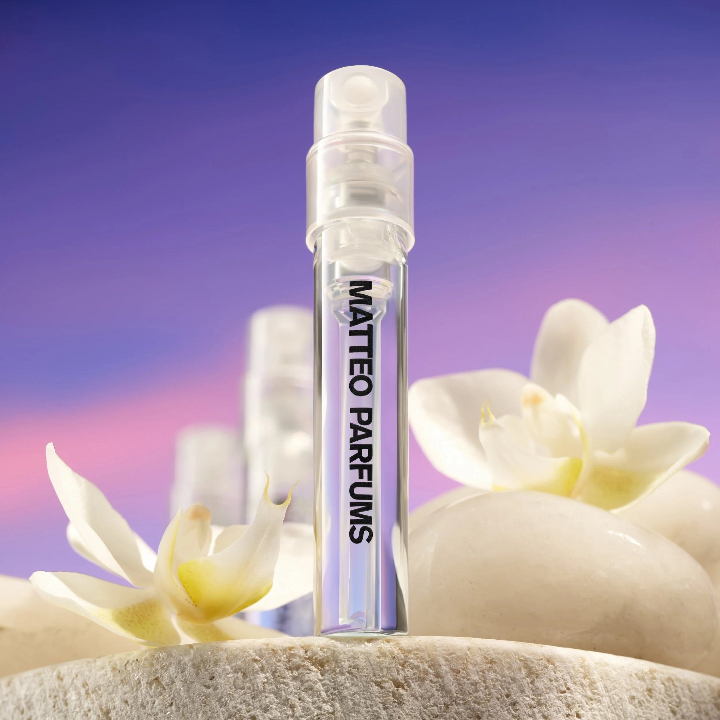 MATTEO PARFUMS perfume spray vials with flowers on a stone surface against a purple gradient background